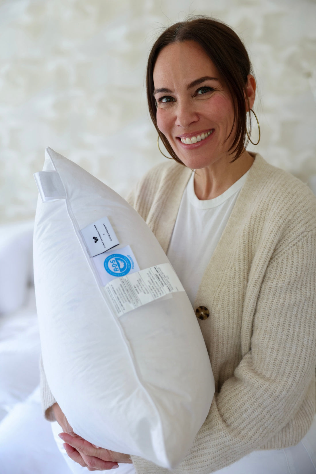 Cara Woodhouse holding a pillow with the Cara Woodhouse × Downright collaboration label