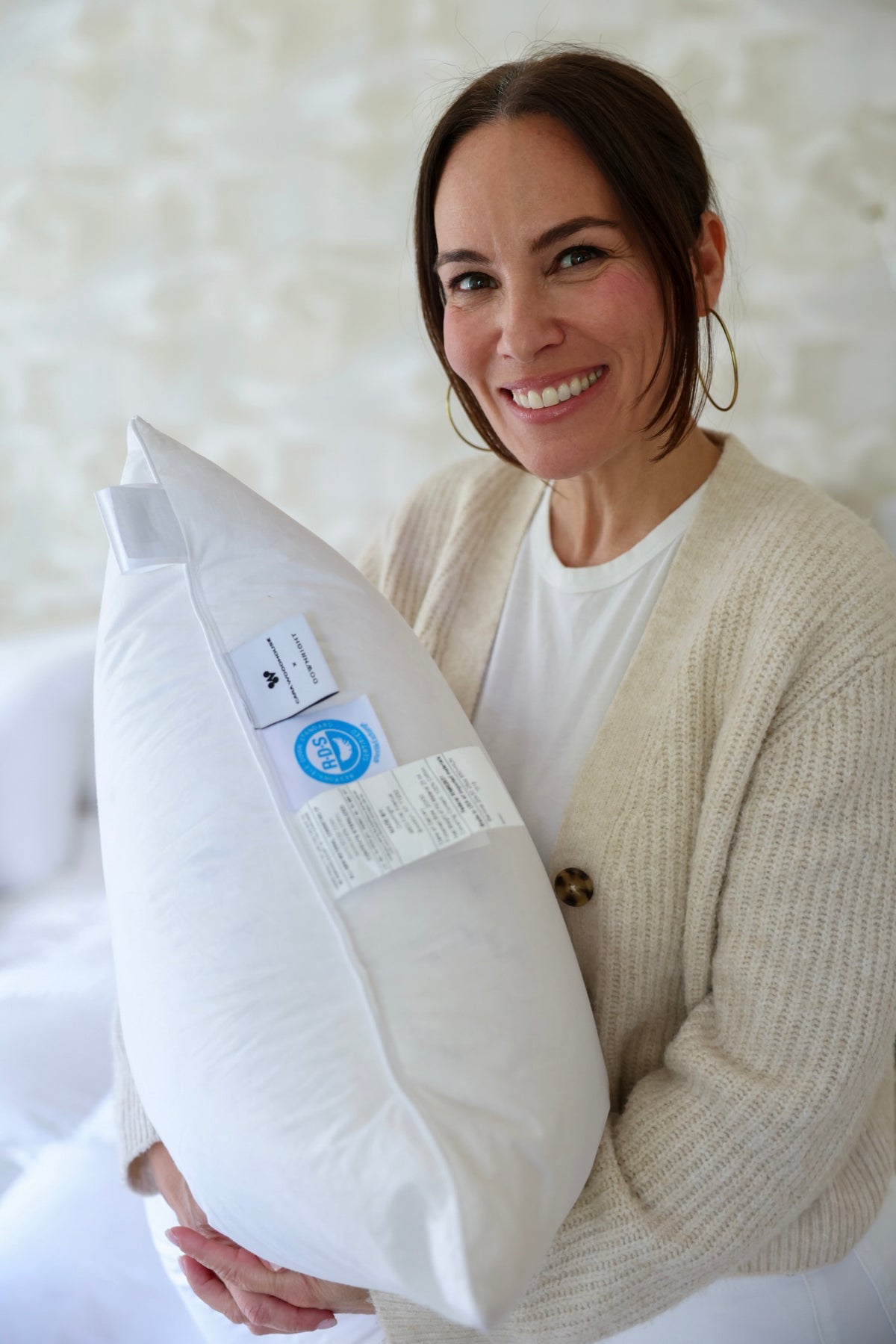 Cara Woodhouse holding a pillow with the Cara Woodhouse × Downright collaboration label