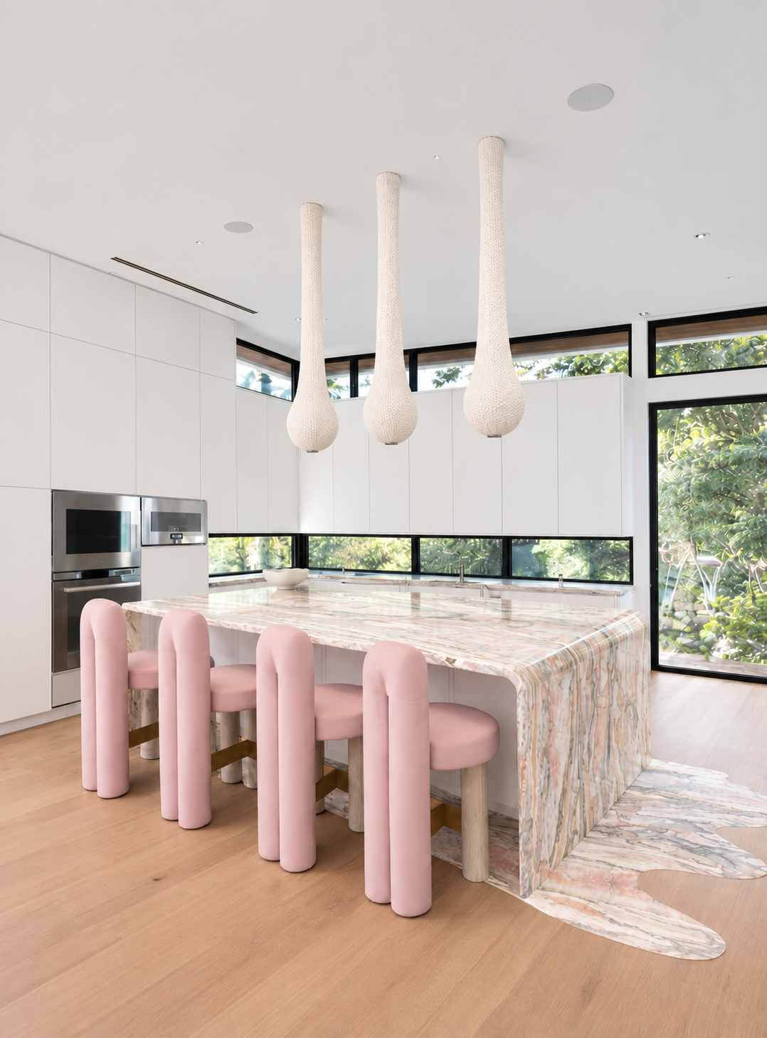 Kendall Miami kitchen with a sculptural marble island flowing into the floor and pink stools